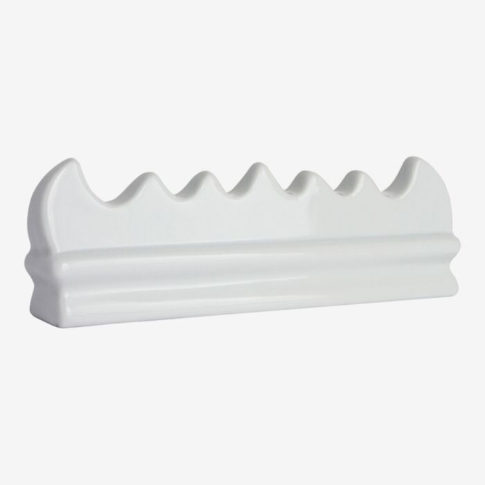 White ceramic brush rest on a white background.